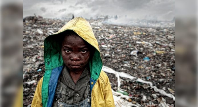 Маленький афроамериканец на фоне мусорной свалки в Мапуту, столице Мозамбика